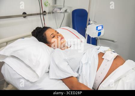 Eine heitere werdende Mutter liegt in einem Krankenhausbett und bereitet sich auf die Ankunft ihres Babys vor. Die friedliche Umgebung spiegelt mütterliche Betreuung, Komfort und Ameise wider Stockfoto