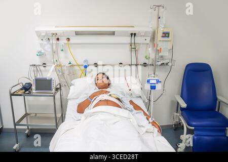 Eine neue Mutter in einem Krankenhausbett, bereit zur Geburt. Umgeben von medizinischer Ausrüstung ruht sie sich ruhig aus und erwartet mit einer se die Ankunft ihres Babys Stockfoto