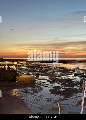 Goldener tropischer Sonnenuntergang über der Küste in Nusa Lembongan, Bali, Indonesien, mit Gezeitenbecken und ruhigem Ozeanhorizont, der warme Abendfarben am Himmel reflektiert. Stockfoto
