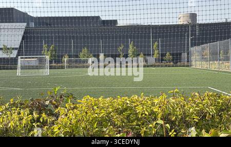 Geräumiger städtischer Spielplatz mit Fußballfeld und farbenfrohen Spielstrukturen an einem sonnigen Tag in der Stadt Stockfoto