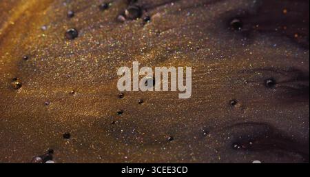 Glitzerstrahl. Lackwasser. Defokussierte gelbe goldene lila Farbe Luftblasen Öl Acrylflüssigkeit schwimmend auf abstrakten Kunst Bokeh Hintergrund. Stockfoto
