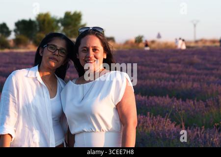 Zwei Frauen stehen in einem Lavendelfeld. Einer von ihnen trägt ein weißes Hemd Stockfoto