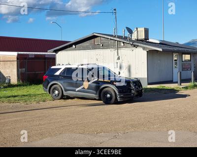 Schwarz-weißes Ford-Auto mit dem Emblem der New Mexico State Police, parkt in der Nähe eines Holzgebäudes Stockfoto