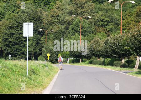 Usti nad orlici - Tschechische republik - 08162025 - Wanderer entlang einer Landstraße gesäumt von Bäumen und Lampenpfosten Stockfoto