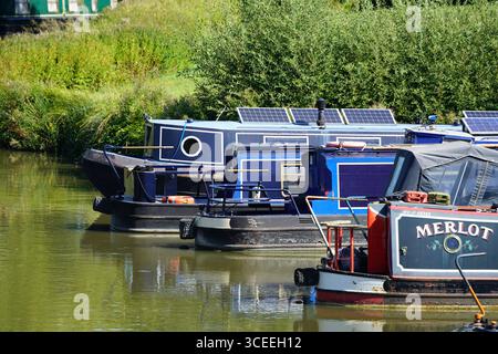 Farbenfrohe Kanalboote legen in einer friedlichen Umgebung am Wasser an. Heyford, England Stockfoto