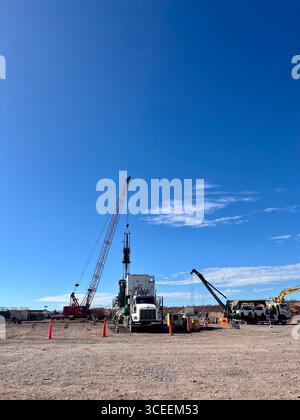 Baustelle mit Kränen, LKW und schweren Geräten unter klarem blauem Himmel an einem sonnigen Tag. Stockfoto