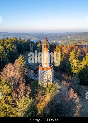 Der Stepanka Aussichtsturm steht hoch vor einem klaren blauen Himmel in Korenov, Tschechien. Umgeben von üppigen grünen Bäumen bietet dieser Blick am Frühjahrmorgen einen atemberaubenden Blick auf das Isergebirge. Stockfoto