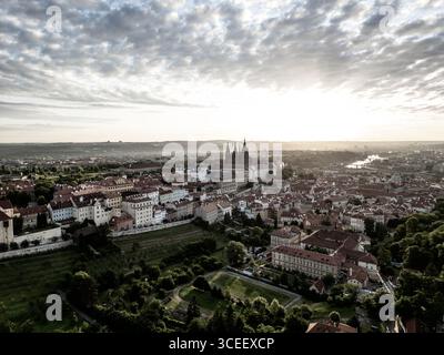Der Sonnenaufgang wirft einen goldenen Glanz über die Prager Burg und die umliegende Stadt und zeigt die atemberaubende Architektur und die ruhige Atmosphäre des frühen morgens in Prag. Stockfoto