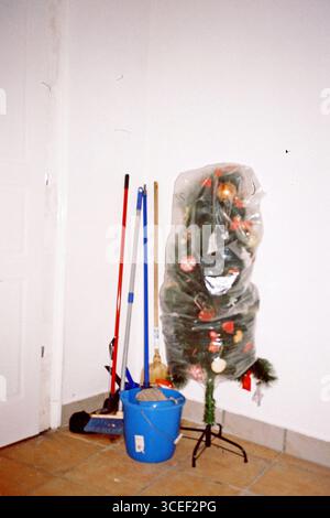 Ecke. Ein Neujahrsbaum in Plastik gewickelt. Daneben befinden sich Putzjogger. Stockfoto