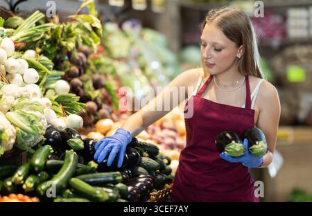 Weibliche Lebensmittelläden bieten reife Zucchini in der Lebensmittelabteilung des Supermarktes an Stockfoto
