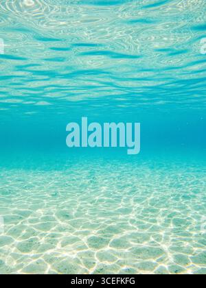 Ein ruhiger Unterwasserblick mit kristallklarem Wasser von San Andres Island, Kolumbien. Das Sonnenlicht erzeugt schöne Reflexionen auf dem Sandboden. Stockfoto