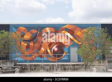 Wandbild eines goldenen Bandes mit einer Kugel und Hörnern auf blauem Hintergrund. Gemalt von Abraham Burciaga in der Art Alley in Sawyer Yards in Houston, Texas. Stockfoto