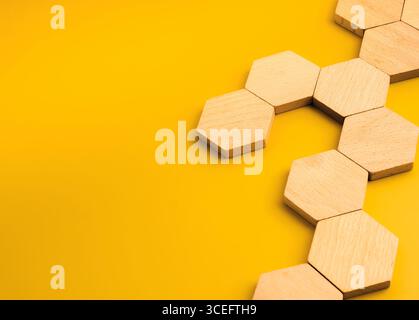Leere sechseckige Holzblöcke für Symbole oder Infografiken, die in Netzwerkmuster auf gelbem Hintergrund angeordnet sind und die Geschäftsstruktur, das System darstellen Stockfoto