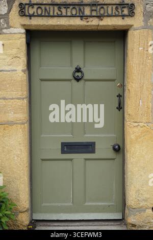 Traditionelle Holztür mit abstraktem Klopfen und Steinumrandung. Stau-on-the-Wold, England Stockfoto
