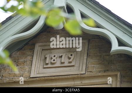 Historische Gebäudefassade mit architektonischen Details und Datum 1879 in Stein gemeißelt. Chipping Norton, England Stockfoto