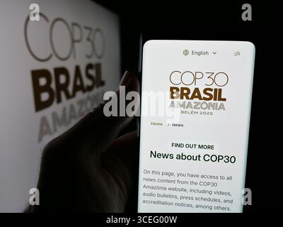 In dieser Fotoabbildung hält eine Person ein Handy mit der Webseite der UN-Klimakonferenz COP30 in Brasilien vor dem Logo. Stockfoto