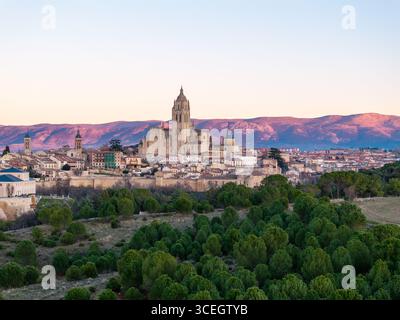 Aus der Vogelperspektive erhebt sich die Kathedrale von Segovia majestätisch über der Skyline der Stadt, eingerahmt von der fernen, sanft beleuchteten Bergkette Segovia, Castilla y León, Spanien. Stockfoto