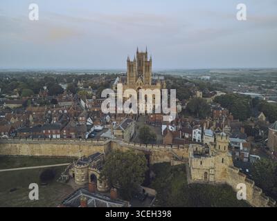 Majestätisch erhebt sich die große Lincoln Cathedral aus der Vogelperspektive über der historischen Stadt, eine Symphonie aus veraltetem Stein vor dem gedämpften Himmel, Lincoln, England, Großbritannien. Stockfoto