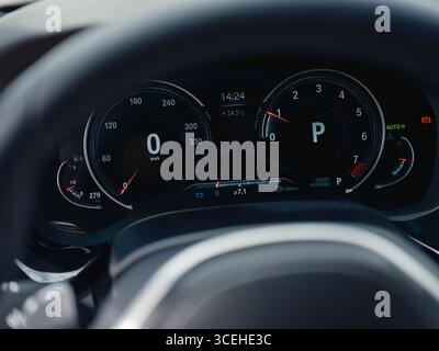 Nahaufnahme des digitalen Armaturenbretts eines modernen Autos. Das Foto zeigt den Tachometer, die Drehzahlanzeige und verschiedene Anzeigen auf einem eleganten Hightech-Geröll Stockfoto