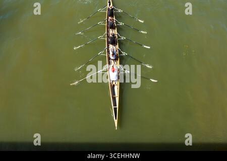 Akademisches Rudern, vier Athleten mit einem Coxswain segeln in einem Boot auf offenem Wasser. Akademischer Ruderwettbewerb. Stockfoto