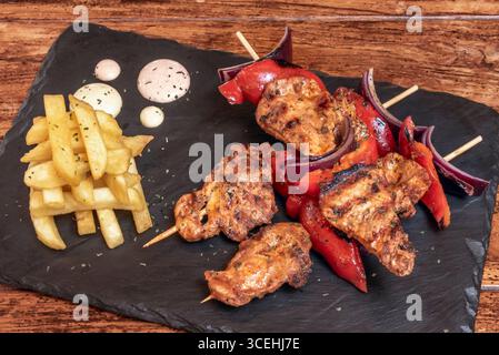 Saftige Spieße peruanischer Antikuchos mit ihrer charakteristischen rötlichen Farbe aus der Panca Chili, perfekt gebräunt über der rauchigen Glut Stockfoto