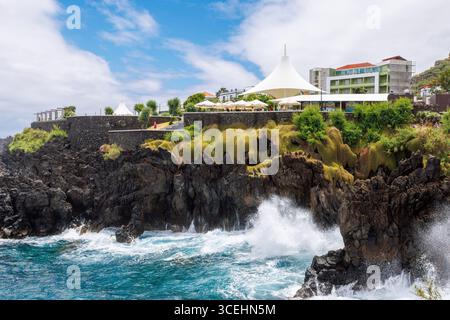 Porto Moniz, Madeira - 7. Juli 2025; wunderschöner Blick auf die Klippen und das Meer, das auf ihnen bricht, große Markise über der Aussichtsplattform. Hohe Qualität Stockfoto