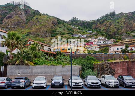 Porto Moniz, Madeira - 5. Juli 2025; Blick auf den Parkplatz und die Stadt Porto Moniz von den Lavapools aus. Die Stadt liegt an den Hängen der Insel. Hallo Stockfoto