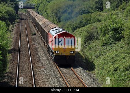 Eine DB Cargo-Lokomotive nähert sich mit einem Zug aus Stahlprodukten aus dem Werk Trostre an der Bahnstrecke von Swansea nach Bridgend der Brücke Stormy No 1 an Stockfoto