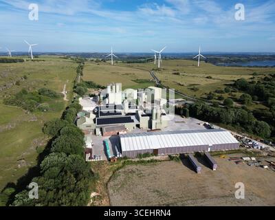 Ein großer Windpark mit mehreren Windturbinen im Hintergrund. Der Windpark befindet sich in einer ländlichen Gegend mit viel Freifläche Stockfoto