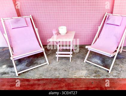 Zwei pastellrosa Liegestühle und kleiner Tisch vor rosa gefliesten Wänden The Hug Store Jalan Penang, George Town penang malaysia Stockfoto