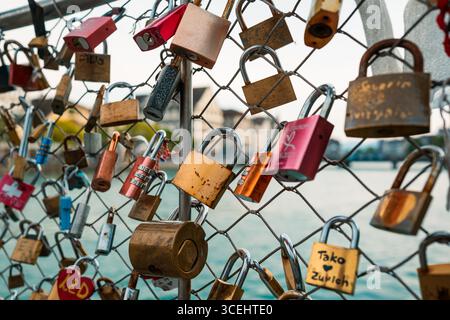 Viele Schlösser oder Vorhängeschlösser hangen und verschlossen an einem Drahtzaun in einer Stadt in Europa. Nahaufnahme, Traditionskonzept für urbane Paare, geringe Tiefenschärfe, wa Stockfoto