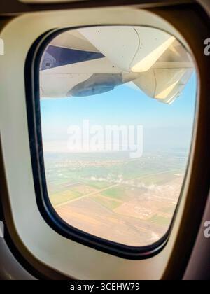 Ansicht vom Flugzeugfenster über grüne Felder unten. Luftfahrt, Flugerlebnis und Verbindung zwischen Himmel und Erde während der Reise. Stockfoto