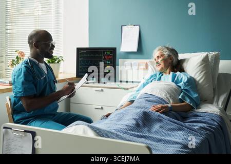 Schwarzer männlicher Arzt berät Senior kaukasische Frau im Krankenhaus Stockfoto