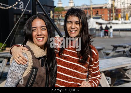 Zwei glückliche Freundinnen umarmen und lächeln draußen und genießen gemeinsam einen sonnigen Tag Stockfoto
