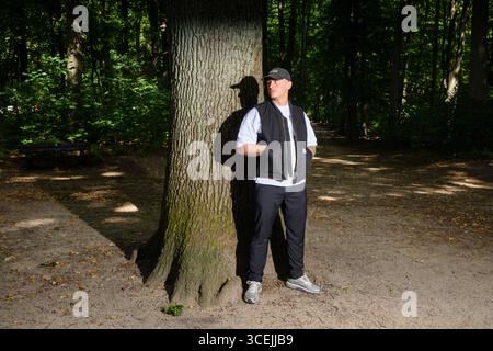 Hamburg, Deutschland. August 2025. Der Musiker und Rapper Disarstar (Gerrit Falius) steht vor einer Eiche im Volkspark Altona. Das neue Album des Hamburger Rappers „Hamburger Aufstand“ erscheint am 29. August. Quelle: Gregor Fischer/dpa/Alamy Live News Stockfoto