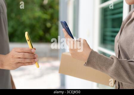 Frau scannt QR-Code für Warenlieferung. Liefermann schickt Lieferexpress. Online-Shop, Papierbehälter, zum Mitnehmen, Postbote, Lieferservice, packa Stockfoto