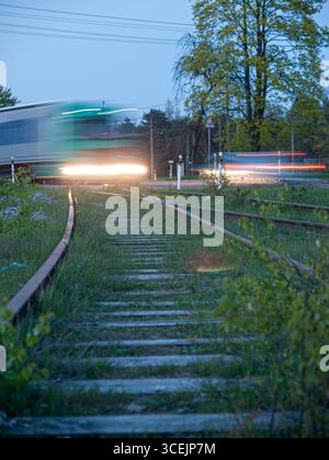 Mai 2009, Estland: Langzeitbelichtungsbild eines Autos, das an einer Eisenbahnkreuzung und einer Straßenkreuzung im Abendlicht überquert. Stockfoto