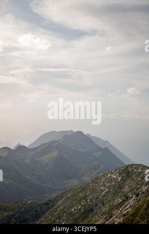 Die Gipfel des Biokovo-Gebirges in der Nähe von Makarska Kroatien bieten einen dramatischen bewölkten Himmel, grüne Hänge und überlagerte Bergrücken, die im Sommer in Dunst versinken Stockfoto