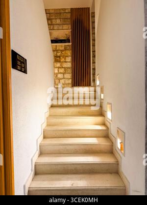 Eine Steintreppe mit warmen Seitenlichtern führt in die obere Etage des Gebäudes. Perspektive, Gastfreundschaft und Innenarchitektur ausgedrückt durch Stockfoto
