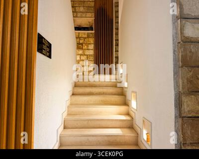 Eine Steintreppe mit warmen Seitenlichtern führt in die obere Etage des Gebäudes. Perspektive, Gastfreundschaft und Innenarchitektur ausgedrückt durch Stockfoto