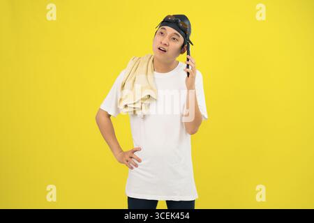 Lächelnder junger Mann, der am Telefon in Schwimmkleidung auf gelbem Hintergrund spricht Stockfoto