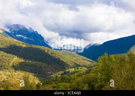 Weitläufige grüne Täler und bewaldete Bergrücken unter dramatischem Himmel, von Ordesa aus gesehen in der Nähe des Monte Perdido in Aragon, den spanischen Pyrenäen. Stockfoto