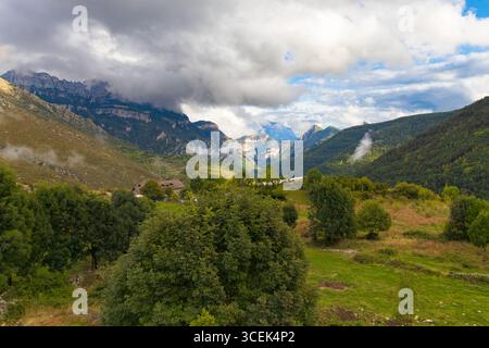 Panoramablick von Asín de Broto mit üppigen Wäldern, felsigen Bergrücken und tief hängenden Wolken über das Ordesa-Tal in den Pyrenäen, Aragon, Spanien. Stockfoto