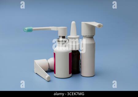 Eine Sammlung verschiedener medizinischer Sprühflaschen, einschließlich Hals- und Nasensprays, ordentlich angeordnet auf einem durchsichtigen blauen Hintergrund. Stockfoto