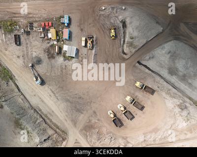 Luftaufnahme der Baustelle mit schweren Maschinen und Muldenkippern – industrielle Erdbewegung und Bergbaubetrieb Stockfoto