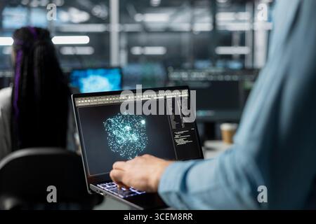 Nahaufnahme der Administratoren, die Laptop im Rechenzentrum verwenden, um Hardware für KI-Aufgaben zu optimieren. IT-Mitarbeiter im Serverraum mit Notebook, automatisiert Systemdiagnosen mithilfe von Deep Learning-Prognosen Stockfoto
