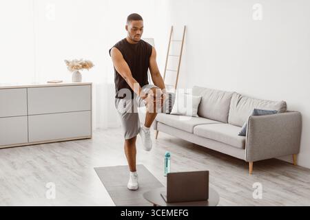 Afrikanischer Mann, Der Zu Hause Knie Zur Brust-Übung Macht Stockfoto