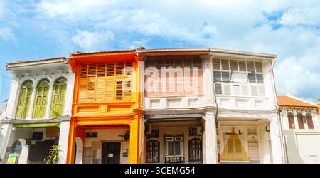 Farbenfrohe Kolonialarchitektur mit lebhaften Geschäften mit Holzläden, strahlend blauem Himmel George Town Penang Island malaysia - Panorama Stockfoto