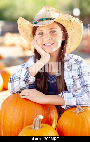 Hübsches Mädchen mit Cowboy-Hut, das den Kürbis-Patch an einem sonnigen Herbsttag genießt. Stockfoto
