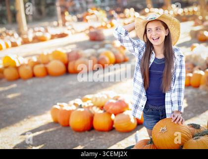 Hübsches Mädchen mit Cowboy-Hut, das den Kürbis-Patch an einem sonnigen Herbsttag genießt. Stockfoto